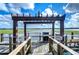 Outdoor view of a wooden dock overlooking the lake with a pergola and a grill at 10100 Sailwinds N Blvd # 106, Largo, FL 33773