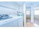 Bright laundry room featuring a modern washer and dryer, wire shelving, and convenient access to the main living area at 10100 Sailwinds N Blvd # 106, Largo, FL 33773