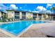 Exterior view of a community pool surrounded by lounge chairs and lush landscaping under a bright blue sky at 10100 Sailwinds N Blvd # 106, Largo, FL 33773