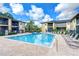 Exterior view of a community pool surrounded by lounge chairs and lush landscaping under a bright blue sky at 10100 Sailwinds N Blvd # 106, Largo, FL 33773