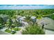 An aerial view of a gray two-story home surrounded by lush trees and near a small pond at 12013 Whistling Wind Dr, Riverview, FL 33579