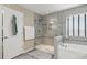 Bright bathroom features a glass enclosed shower, tile accents, soaking tub, and window at 12013 Whistling Wind Dr, Riverview, FL 33579