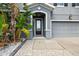 Close-up of home's entrance, showing front door, two-car garage, and tropical landscaping at 12013 Whistling Wind Dr, Riverview, FL 33579