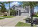 Gray two-story home with an attached two-car garage, complemented by tropical landscaping at 12013 Whistling Wind Dr, Riverview, FL 33579