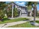 Charming gray two-story home with tropical landscaping and a well-manicured lawn at 12013 Whistling Wind Dr, Riverview, FL 33579