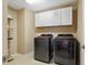Laundry room with tile floors, white cabinets, modern appliances, and storage space at 12013 Whistling Wind Dr, Riverview, FL 33579