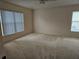 Large carpeted bedroom with neutral walls and two windows at 2421 E Del Webb Blvd, Sun City Center, FL 33573