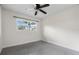 This simple bedroom has a ceiling fan, a large window for natural light, and neutral gray carpet at 3612 W Leila Ave, Tampa, FL 33611