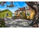 Charming yellow cottage with a gravel driveway and lush landscaping at 5407 29Th S Ave, Gulfport, FL 33707