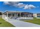 Gray manufactured home with covered porch and screened enclosure at 39053 Flora Ave, Zephyrhills, FL 33542