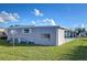 Gray manufactured home with covered carport and green lawn at 39053 Flora Ave, Zephyrhills, FL 33542