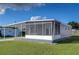 Gray manufactured home with screened porch and landscaping at 39053 Flora Ave, Zephyrhills, FL 33542