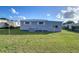 Gray manufactured home with AC unit and spacious yard at 39053 Flora Ave, Zephyrhills, FL 33542