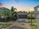 Charming single-Gathering home featuring a two-car garage and lush landscaping during sunset at 16912 Yellow Pine St, Wimauma, FL 33598