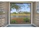 Peaceful water view with mature trees as seen from inside the home's window with shutters at 390 Cypress Creek Cir, Oldsmar, FL 34677