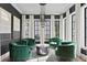 Elegant sitting room with stylish decor, large windows, and comfortable green chairs arranged around a modern table at 5811 Mariner St, Tampa, FL 33609