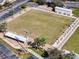 Aerial view of the lawn bowling field with benches, palm trees and a storage building at 1715 S Pebble Beach Blvd, Sun City Center, FL 33573