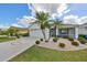 Single-story home with landscaped yard, driveway, and two palm trees at 1120 Emerald Dunes Dr, Sun City Center, FL 33573