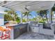 Covered outdoor kitchen with grill, sink, and bar seating at 16434 Redington Dr, Redington Beach, FL 33708