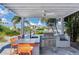 Covered outdoor kitchen with grill, sink, and bar seating at 16434 Redington Dr, Redington Beach, FL 33708