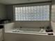 Bathroom featuring a large soaking tub and glass block window at 1003 W Mahoney St, Plant City, FL 33563