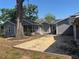 Exterior view of a gray home with a screened porch, complemented by a sand-filled yard and mature trees at 1003 W Mahoney St, Plant City, FL 33563