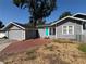 Charming gray home featuring a bright blue door, complemented by a brick driveway and lush green landscaping at 1003 W Mahoney St, Plant City, FL 33563