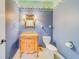 Half bath featuring blue patterned wallpaper, an ornate vanity, and decorative mirror at 1135 Candler Rd, Clearwater, FL 33765