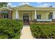 Charming home entrance with a covered porch, brick accents, and lush landscaping at 2501 Rustic Oaks Dr, Lutz, FL 33559
