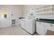 Well-lit laundry room with modern washer, dryer, ample shelving and counter space for convenience at 2501 Rustic Oaks Dr, Lutz, FL 33559