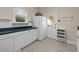 Practical laundry room with white cabinetry, window, and shelving for efficient organization at 2501 Rustic Oaks Dr, Lutz, FL 33559