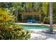 Private pool with blue lounge, a fire pit, and lush tropical landscaping, perfect for relaxation at 2501 Rustic Oaks Dr, Lutz, FL 33559