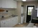 Galley kitchen with white cabinets, stackable washer/dryer, and exterior access at 3402 W Obispo St, Tampa, FL 33629