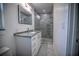 Modern bathroom with gray tile shower, granite vanity, and white cabinets at 1042 Idlewild N Dr, Dunedin, FL 34698