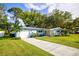 Light blue house with a large yard and driveway at 1042 Idlewild N Dr, Dunedin, FL 34698