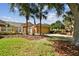 House exterior featuring a tan garage door, stone accents, and palm trees at 13141 Palmilla Cir, Dade City, FL 33525