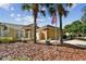 Tan house with a landscaped yard, palm trees, and a flag at 13141 Palmilla Cir, Dade City, FL 33525