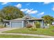 One-story home with gray exterior, two-car garage, and landscaped yard at 13229 Golf Ridge Pl, Hudson, FL 34669