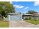 Gray exterior house with two car garage and lush landscaping at 13229 Golf Ridge Pl, Hudson, FL 34669