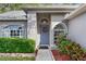 Home's entrance featuring an elegant blue door, lush landscaping, and brick walkway at 16011 Royal Aberdeen Pl, Odessa, FL 33556