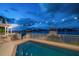 Relaxing pool area with string lights and waterfront views at dusk at 18 Winston Dr, Belleair, FL 33756