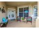 Inviting front porch with wicker chairs and tiled flooring at 2681 Whispering Pine Ln, North Port, FL 34287