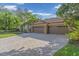 Three-car garage and paver driveway with lush landscaping at 4907 Londonderry Dr, Tampa, FL 33647