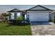 Charming home featuring a manicured lawn, brick driveway, two-car garage, and modern blue exterior at 11207 Shoreline Trl, Parrish, FL 34219