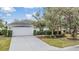 House exterior showcases a white facade, two-car garage, and manicured lawn at 10230 Old Tampa Bay Dr, San Antonio, FL 33576