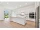 Bright, white kitchen with a large center island, modern appliances, and access to the outdoor patio at 11208 Shoreline Trl, Parrish, FL 34219