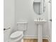 A neutral powder room featuring a pedestal sink, toilet, and oval mirror at 11208 Shoreline Trl, Parrish, FL 34219