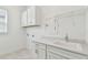 Bright laundry room featuring white cabinetry, granite countertops, a sink, and convenient shelving for storage at 11477 Waterway Dr, Parrish, FL 34219