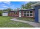 Brick ranch home with blue accents and a well-maintained lawn at 12905 N Oregon Ave, Tampa, FL 33612