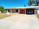 Single-story home featuring a vibrant exterior, covered parking, and a long driveway for multiple vehicles at 552 Trade Winds Dr, Dunedin, FL 34698